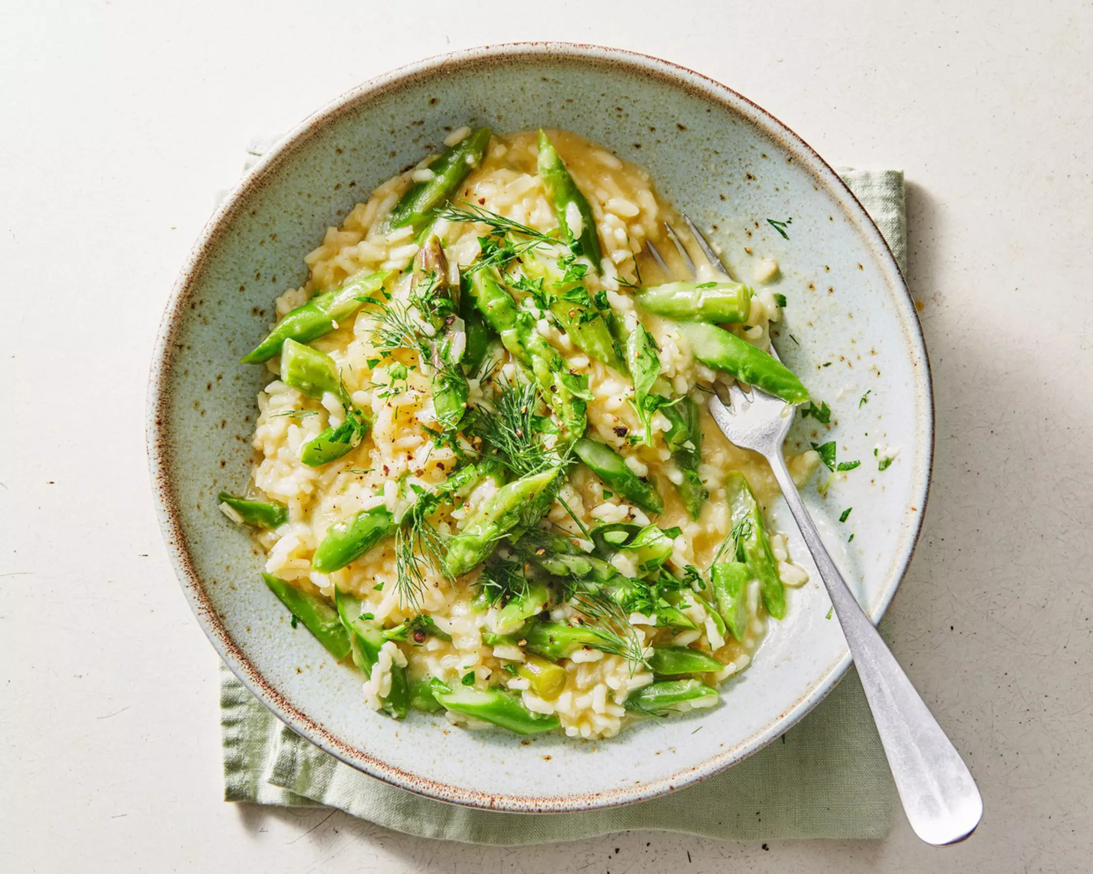 Cremiger Risotto mit grünen Spargeln, Petersilie und Dill in einer Schale